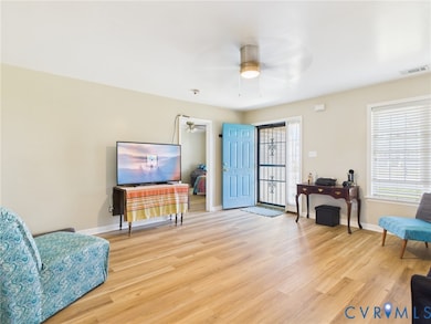Living area featuring healthy amount of natural light, light wood-type flooring, and a ceiling fan
