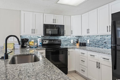 Kitchen with black appliances, light stone countertops, white cabinets, a textured ceiling, and tasteful backsplash