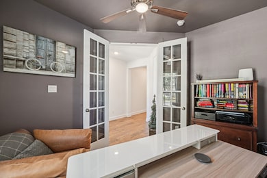Office area with wood finished floors, ceiling fan, and french doors
