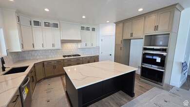 Kitchen featuring a kitchen island, light stone counters, tasteful backsplash, recessed lighting, and light wood-style floors