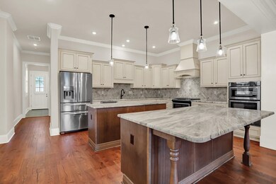 Kitchen featuring stainless steel appliances, a center island, cream cabinets, custom range hood, and tasteful backsplash