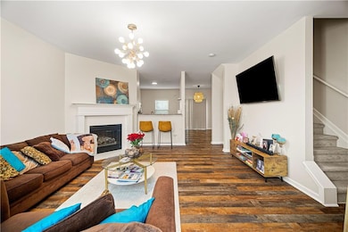 Living room with wood finished floors, stairs, a glass covered fireplace, and a chandelier