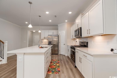 Kitchen featuring an island with sink, light hardw