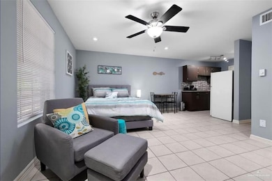 Bedroom featuring freestanding refrigerator, light tile patterned flooring, a ceiling fan, and recessed lighting