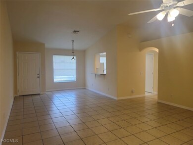 Empty room featuring lofted ceiling, a ceiling fan, light tile patterned flooring, and arched walkways