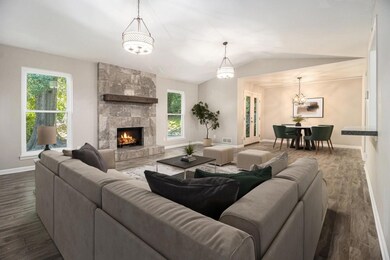 Vaulted Fireside Family Room complete with a Striking Stone Fireplace and Wood Mantel flows effortlessly into the Dining Room