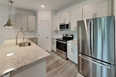 Kitchen with light stone counters, sink, stainless
