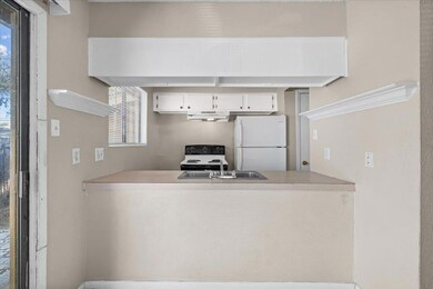 Kitchen with freestanding refrigerator, light countertops, electric range, white cabinets, and under cabinet range hood