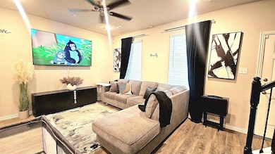 Living room featuring a textured ceiling, wood finished floors, and a ceiling fan