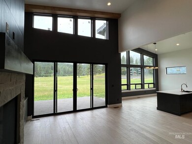 Living room featuring a high ceiling, light wood finished floors, a stone fireplace, recessed lighting, and plenty of natural light