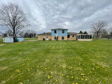 back of house featuring an outdoor structure, a sunroom, a yard, and brick siding