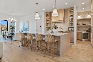 Kitchen featuring backsplash, light stone countertops, decorative light fixtures, light wood finished floors, and recessed lighting