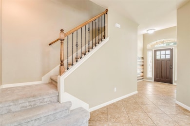 Tiled foyer entrance with stairway and baseboards