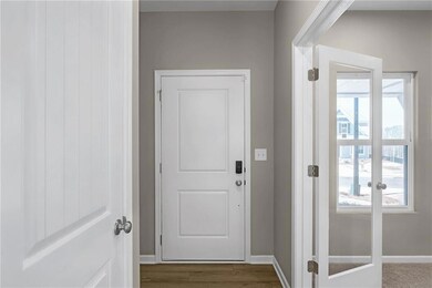 Doorway with dark wood-type flooring and baseboard