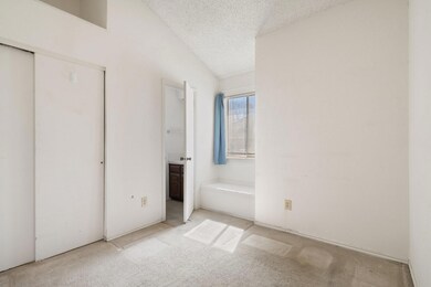 Unfurnished bedroom with a textured ceiling, conne