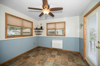 Empty room featuring a wainscoted wall, plenty of natural light, stone finish flooring, and a ceiling fan