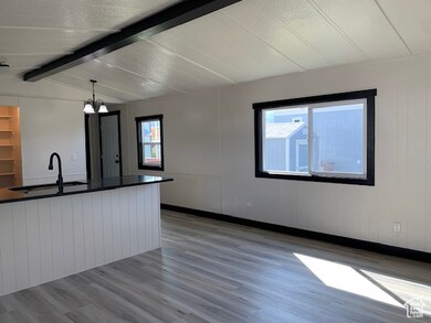 Nice bright frond view of Family/Living room and Kitchen featuring wood-style finish floors, dark quartz countertops.