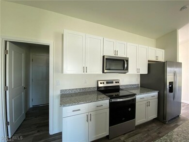 Kitchen with light stone countertops, white cabine