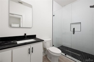 Full bath featuring wood finished floors, a shower stall, toilet, and vanity