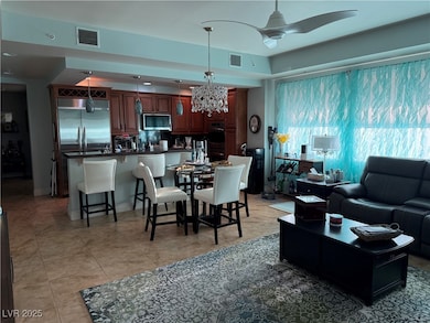 Living area featuring light tile patterned floors, a chandelier, and ceiling fan