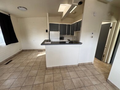 Kitchen featuring dark cabinets, a peninsula, dark countertops, vaulted ceiling, and freestanding refrigerator