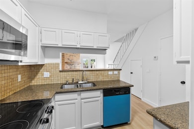 Kitchen featuring electric range oven, white cabinetry, and dishwashing machine