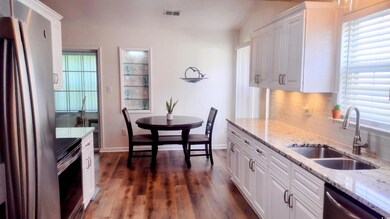 Kitchen with stainless steel appliances, decorative backsplash, white cabinets, dark wood-type flooring, and healthy amount of natural light