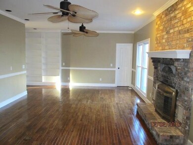Living room with beautiful, refinished wood floors and built-in book shelves.