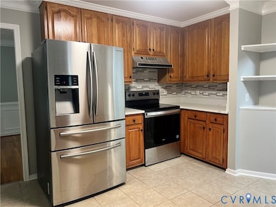 Kitchen featuring ornamental molding, stainless steel appliances, brown cabinetry, light countertops, and decorative backsplash