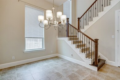 The elegant formal dining room features tile flooring, a luxe chandelier, upgraded baseboards, designer paint and a gleaming window for natural lighting.