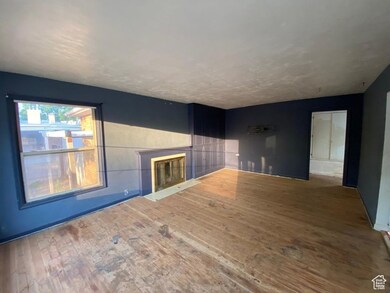 Unfurnished living room featuring a fireplace with flush hearth and wood finished floors