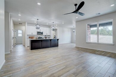 Open Kitchen, Dining and living with ceiling fan and lantern chandelier and pendants, plenty of natural light, light hardwood / wood-style tile floors.