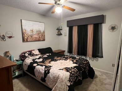 Bedroom with ceiling fan, a textured ceiling, and 