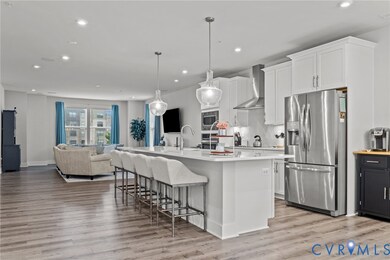 Kitchen featuring stainless steel appliances, open floor plan, white cabinets, a kitchen island with sink, and recessed lighting