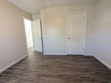 Unfurnished bedroom with dark wood-style floors and baseboards