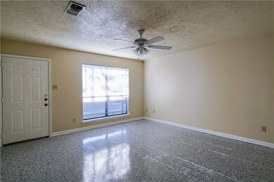 Empty room with a textured ceiling, speckled floor