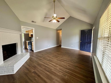 Unfurnished living room featuring lofted ceiling, ceiling fan, a fireplace, dark wood-style floors, and baseboards