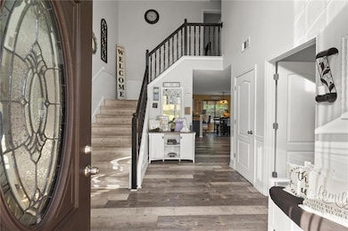 Foyer entrance with stairs, visible vents, dark wo