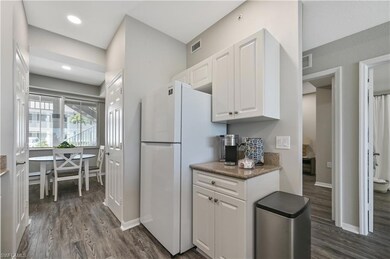 Kitchen with dark wood-type flooring, white cabinetry, dark stone counters, freestanding refrigerator, and recessed lighting