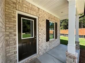 Property entrance featuring a porch and brick siding