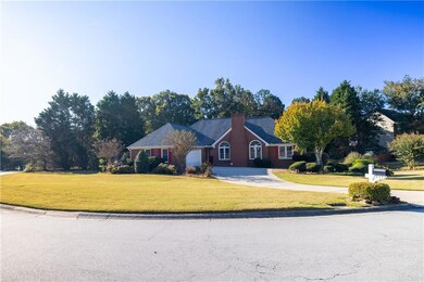 Ranch-style house featuring a front yard, concrete driveway, and a chimney