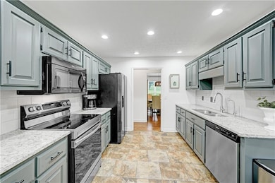 Kitchen featuring appliances with stainless steel finishes, decorative backsplash, light stone finish flooring, recessed lighting, and light stone counters