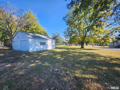 View of green lawn with an outdoor structure and a garage