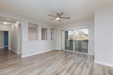 Empty room with ceiling fan, light wood finished f