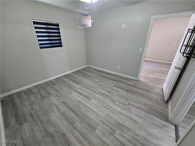 Spare room featuring light wood-type flooring and a wall mounted air conditioner