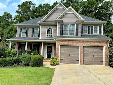 View of front of property with covered porch, a garage, concrete driveway, a front yard, and roof with shingles