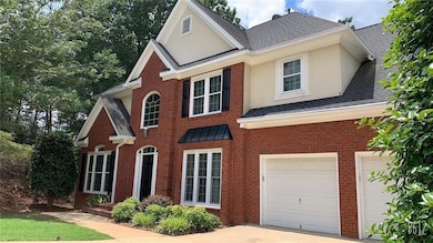 Traditional-style house with a shingled roof, brick siding, an attached garage, and concrete driveway