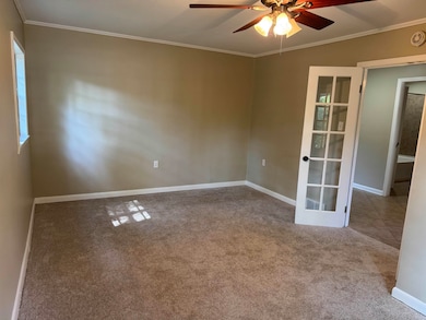 Carpeted empty room with ornamental molding, ceiling fan, and french doors