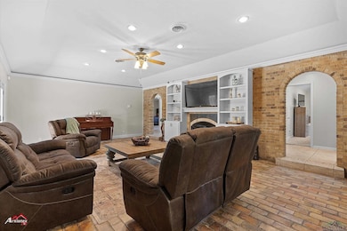 Living area featuring arched walkways, a ceiling fan, recessed lighting, brick wall, and ornamental molding