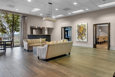 Living room with hardwood / wood-style flooring, a drop ceiling, and a high ceiling